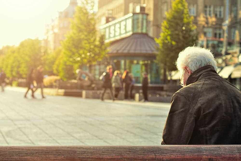 retired man sitting on a park bench in the city