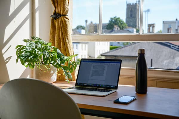 laptop on a desk looking out of a window at a city